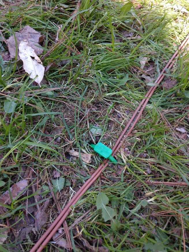 brown wire with green peg installed over it on the ground