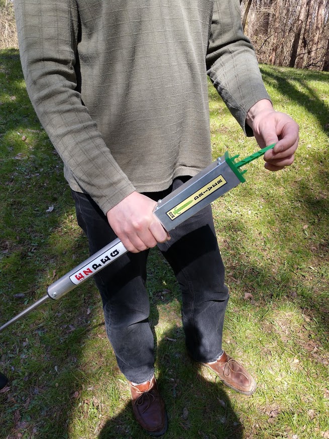 man holding ezpeg bio driver tool inserting green plastic peg landscape staple